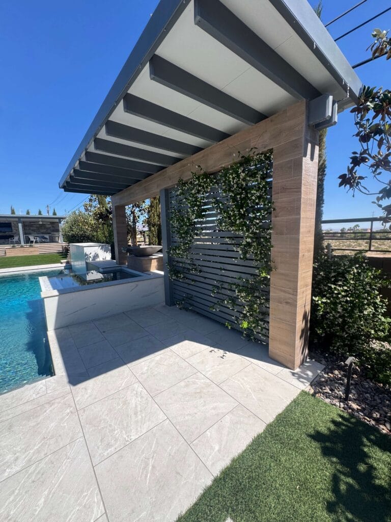 Modern pergola with integrated spa and lounge area overlooking a resort-style swimming pool and manicured landscape.