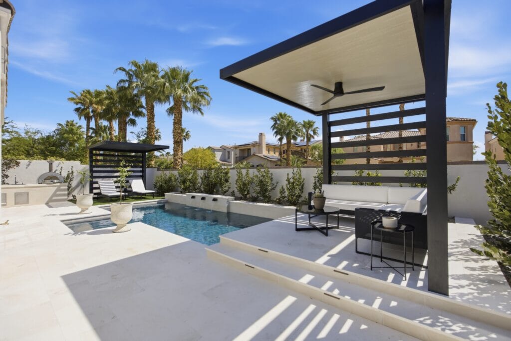 Modern rooftop pool and spa with black pergola, lounge seating, and palm trees overlooking Mediterranean architecture.