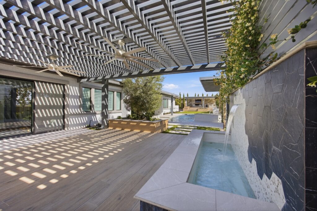 Modern backyard patio with pergola, wooden deck, and sleek spa featuring clean lines and contemporary design.